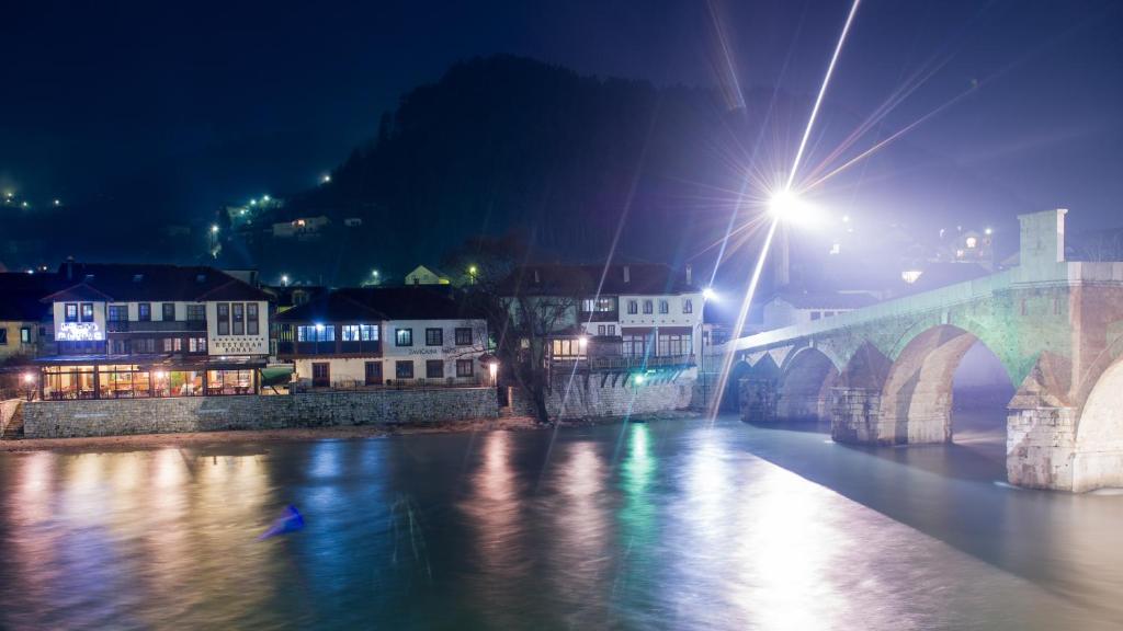 een brug over een rivier met gebouwen 's nachts bij Hotel Konak Konjic in Konjic