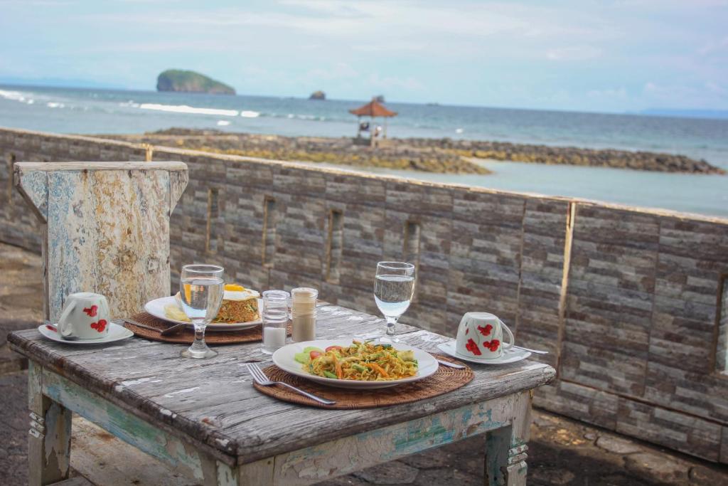 - une table avec une assiette de nourriture sur la plage dans l'établissement Temple Cafe & Cottages, à Candidasa