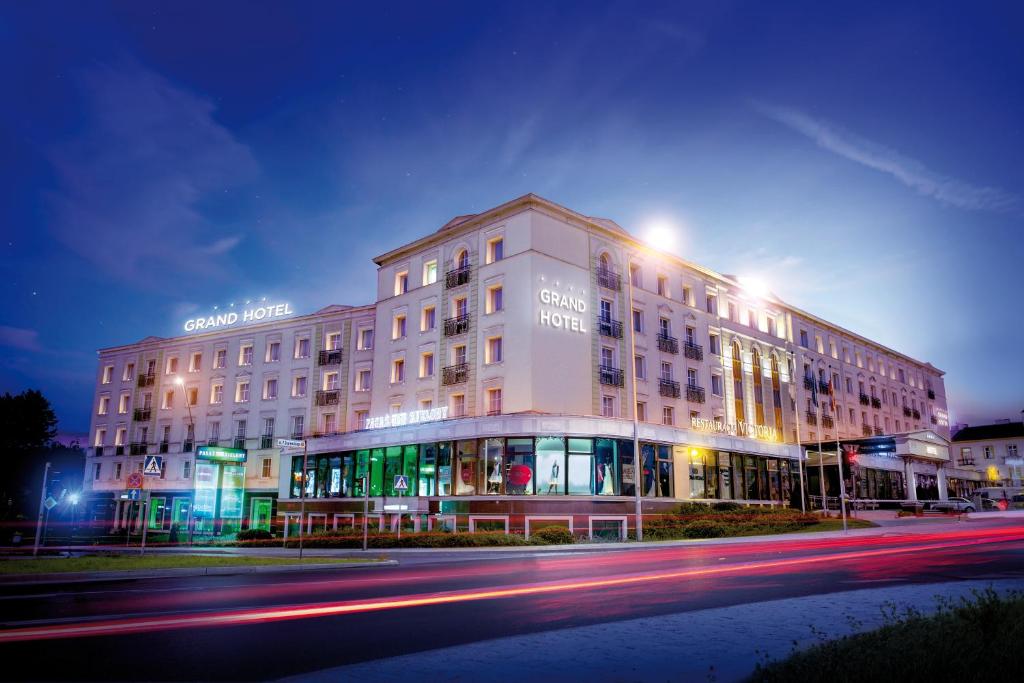 ein Gebäude an einer Straße in der Nacht mit Lichtern in der Unterkunft GRAND HOTEL Kielce in Kielce