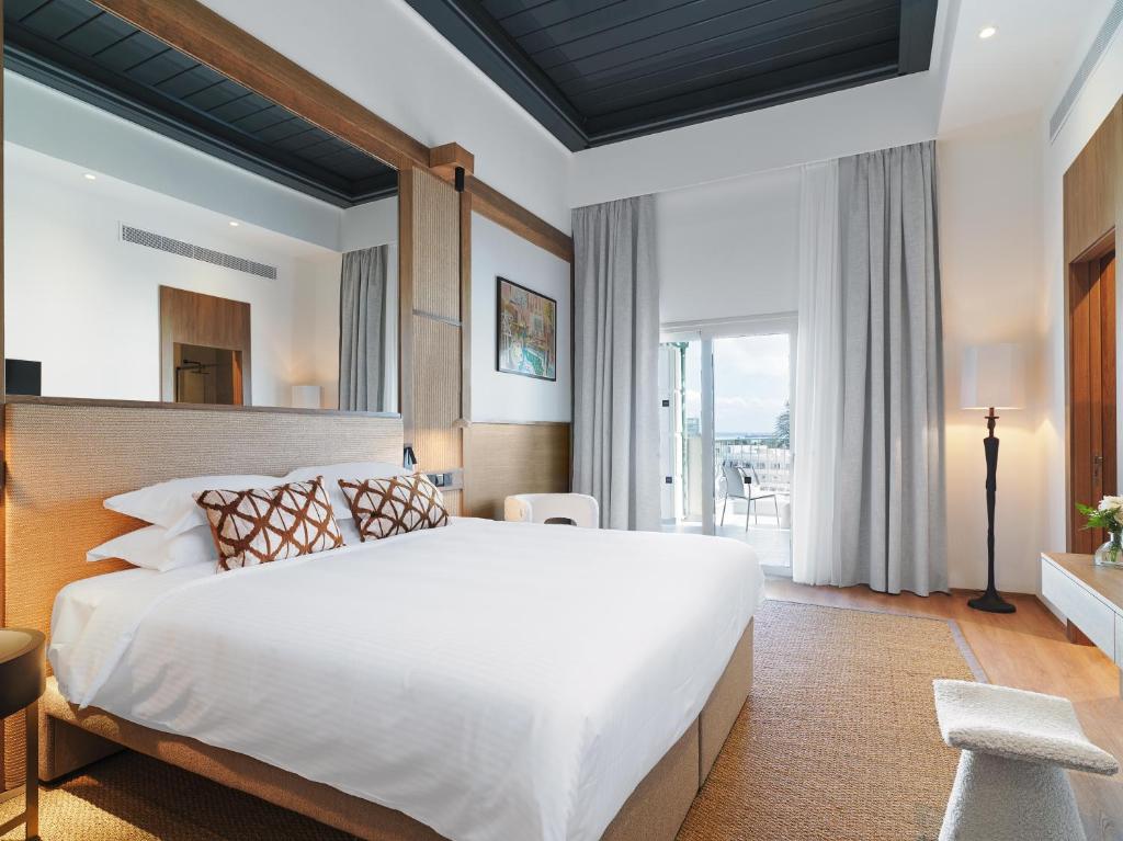 - une chambre avec un grand lit et une grande fenêtre dans l'établissement Leonardo Boutique Hotel Larnaca, à Larnaka