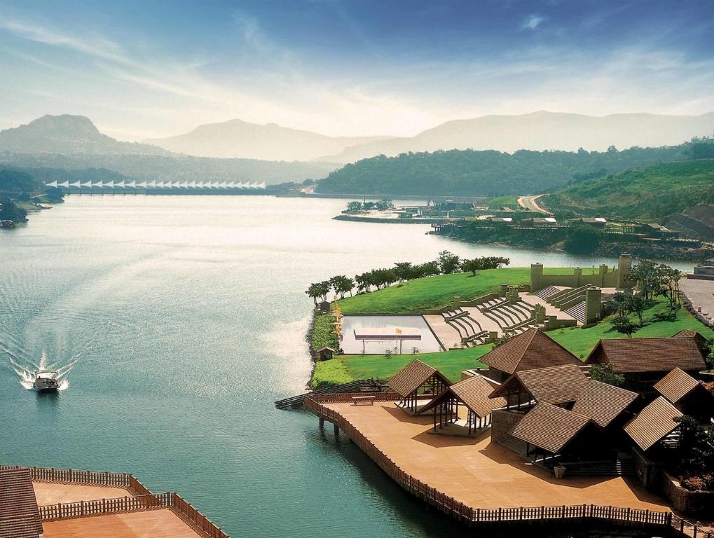 an aerial view of a lake with houses and a boat at Aamby Valley City in Lonavala