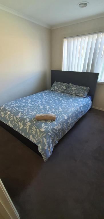 a bedroom with a bed with a blue comforter at Home stay in Wyndham Vale