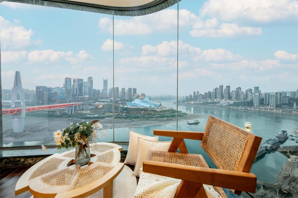 een kamer met 2 tafels en stoelen en een groot raam bij Baihong.Riverview Apartment in Chongqing