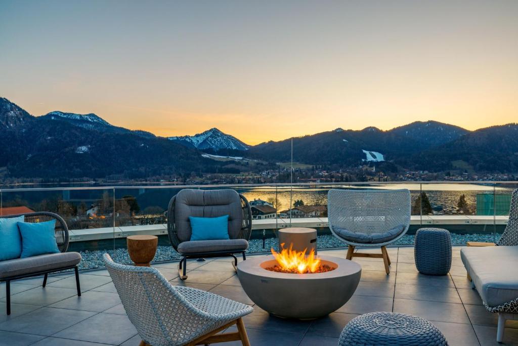 eine Terrasse mit Stühlen und eine Feuerstelle mit Bergen im Hintergrund in der Unterkunft Caro & Selig, Tegernsee, Autograph Collection in Tegernsee