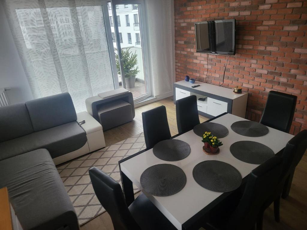 ein Wohnzimmer mit einem Tisch, Stühlen und einem Sofa in der Unterkunft Apartament MAJA (przy Aquaparku w Redzie) in Rumia