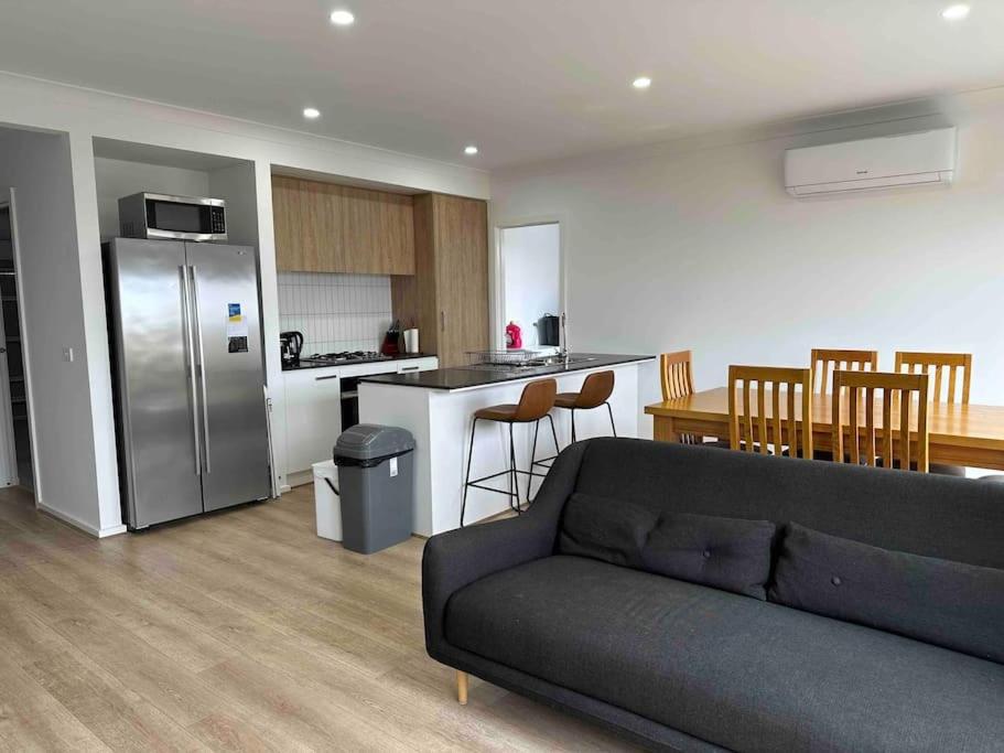 a living room with a couch and a kitchen at Wonderful Jubilee Estate House in Wyndham Vale