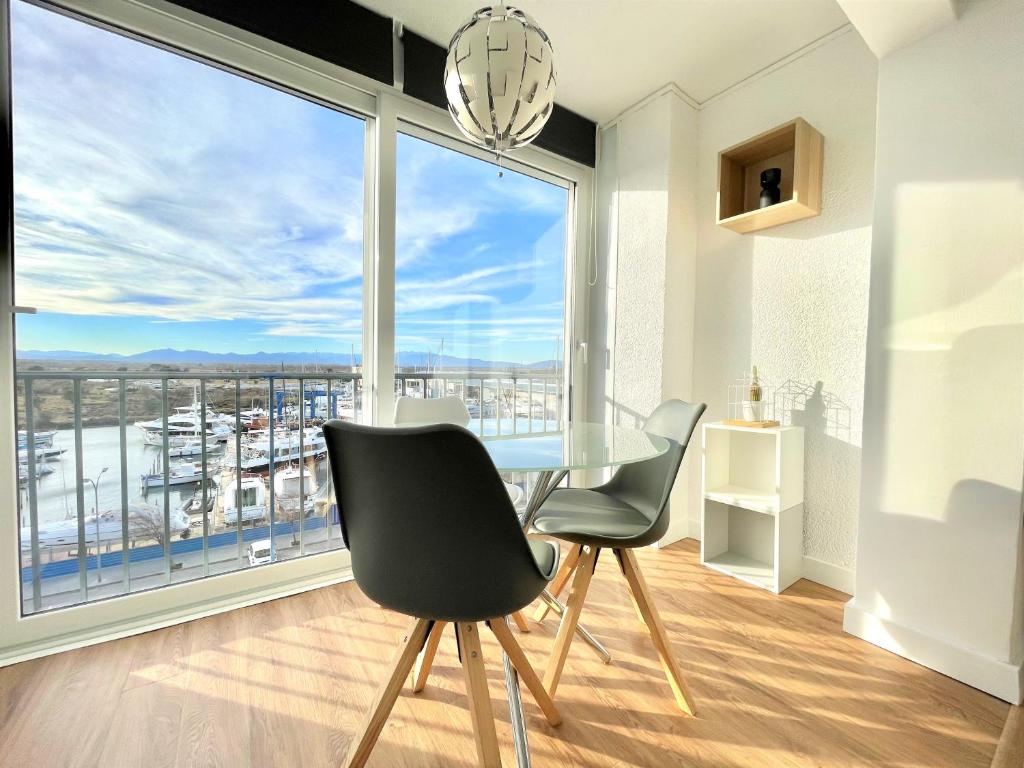 a dining room with a table and two chairs and a large window at Holidays Penthouse vues panoramiques sur le Port naval,un séjour élégant assuré " Wifi Pàrquing gratuït in Roses