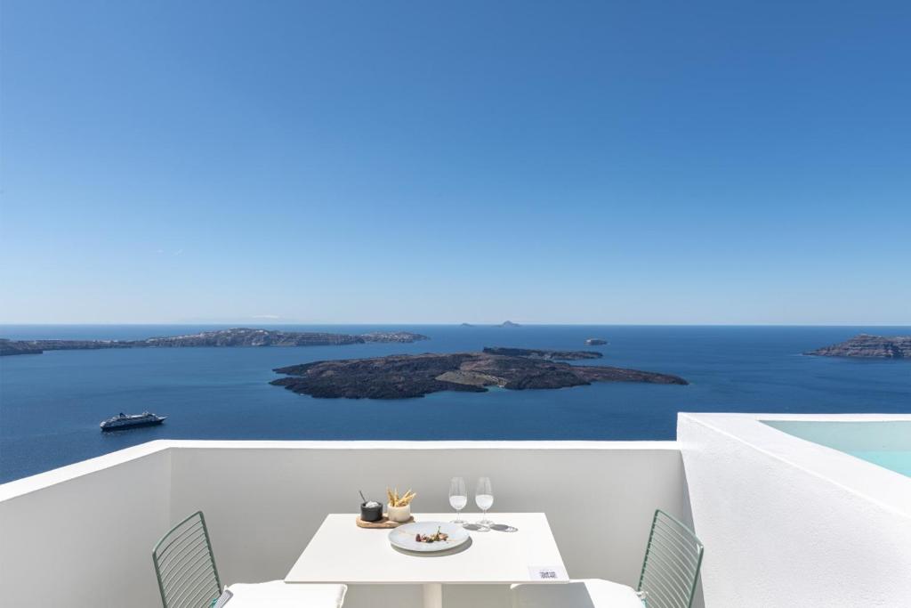 un balcone bianco con tavolo, sedie e vista sull'oceano di Akra Suites & Spa a Imerovigli