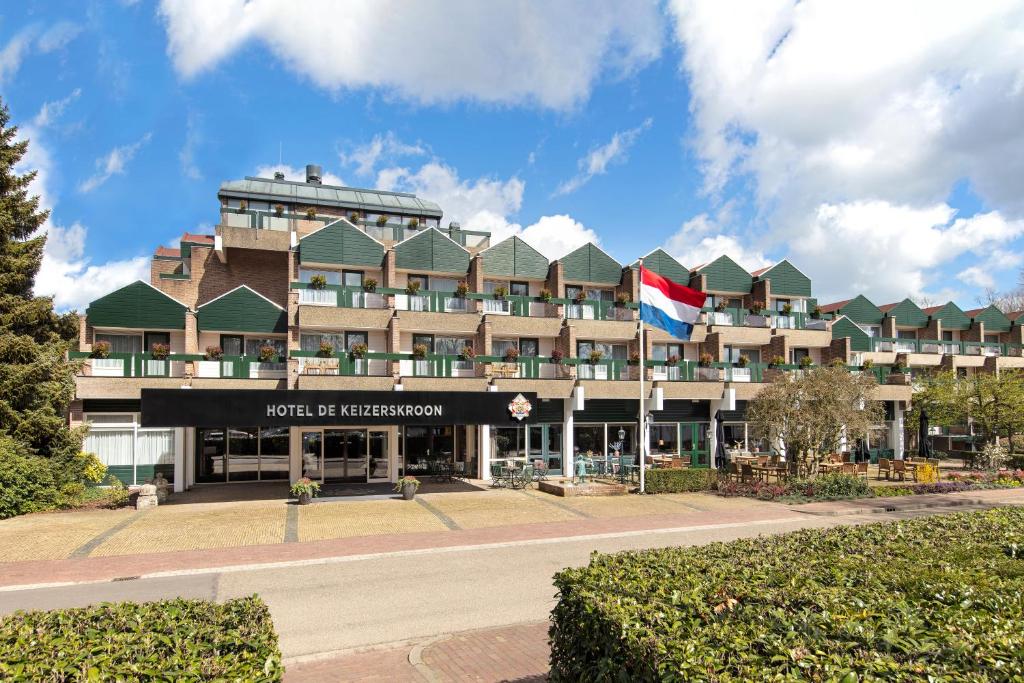 un hotel con una bandiera di fronte a un edificio di Bilderberg Hotel De Keizerskroon ad Apeldoorn