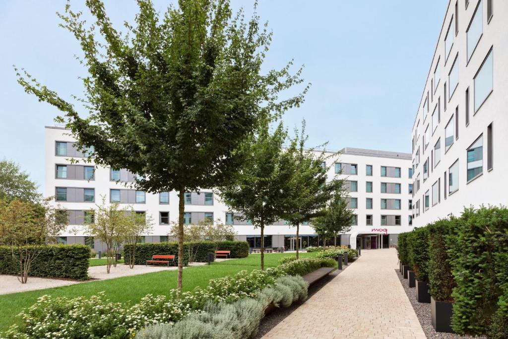 a courtyard with trees and a building at Moxy Munich Ostbahnhof in Munich