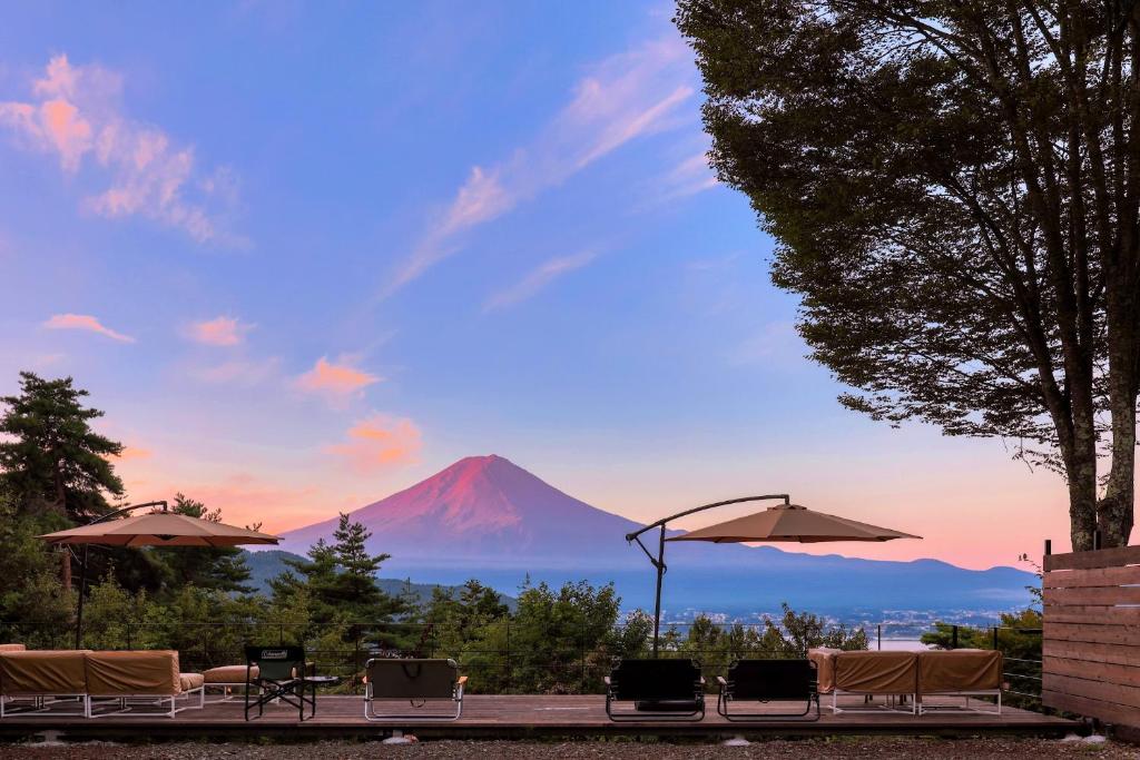 uma vista para uma montanha com cadeiras e guarda-sóis em Retreat Camp Mahoroba em Fujikawaguchiko