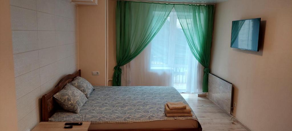 een slaapkamer met een bed en een raam met groene gordijnen bij Harmony on Andrew descent in Kiev