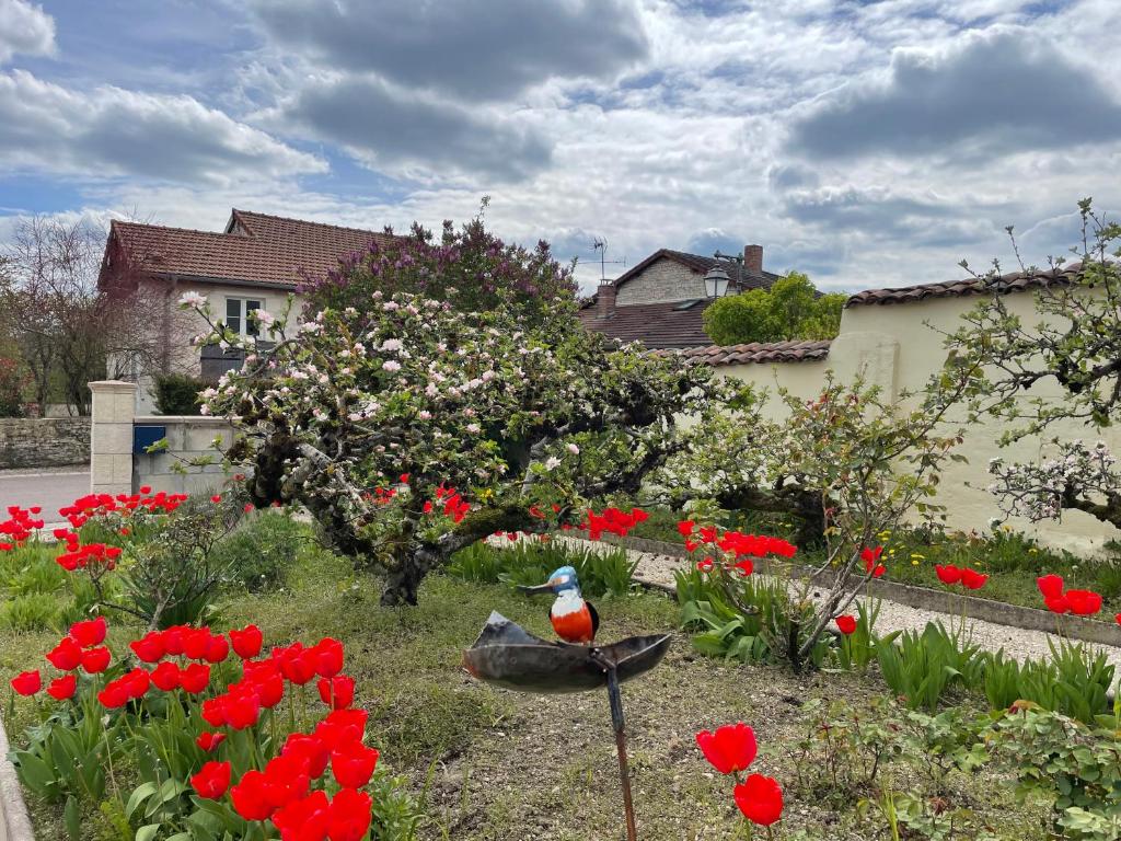 un oiseau assis dans un jardin avec des fleurs rouges dans l'établissement Gîte L'entre 2, 7personnes à COLOMBEY proche de Nigloland, à Colombey-les-Deux-Églises