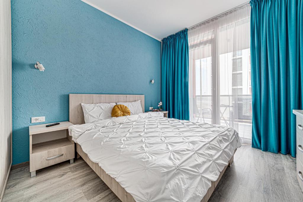 een slaapkamer met een groot bed met blauwe muren bij ARI - AFI Mall Luxurious Apartments with Free Parking in Arad