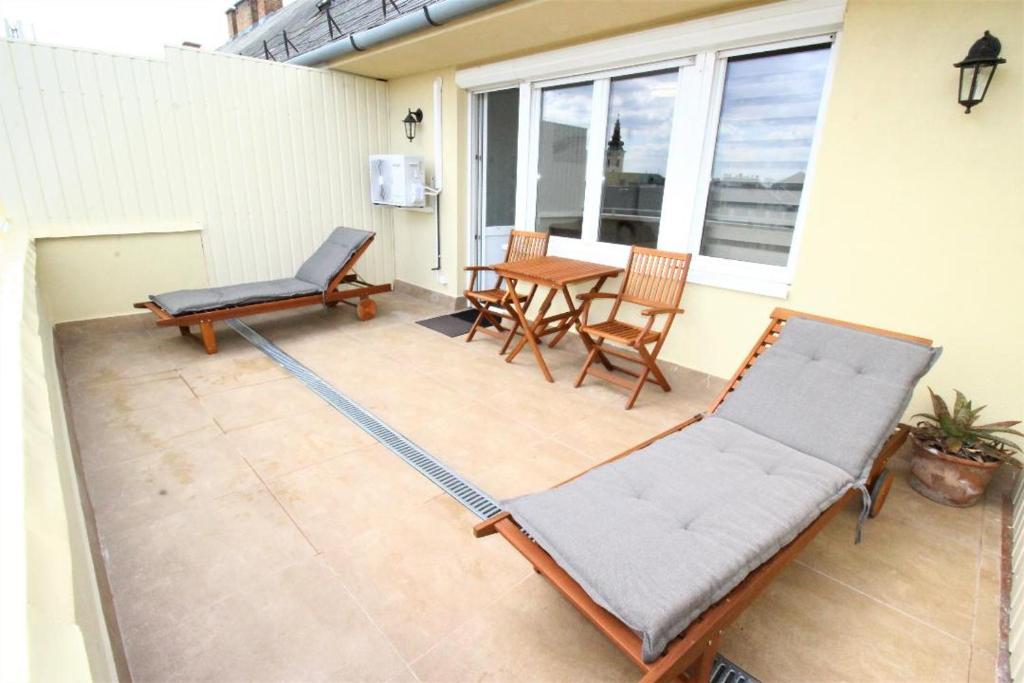 un patio con 2 sillas y una mesa en una casa en Rest House Apartman, en Nyíregyháza