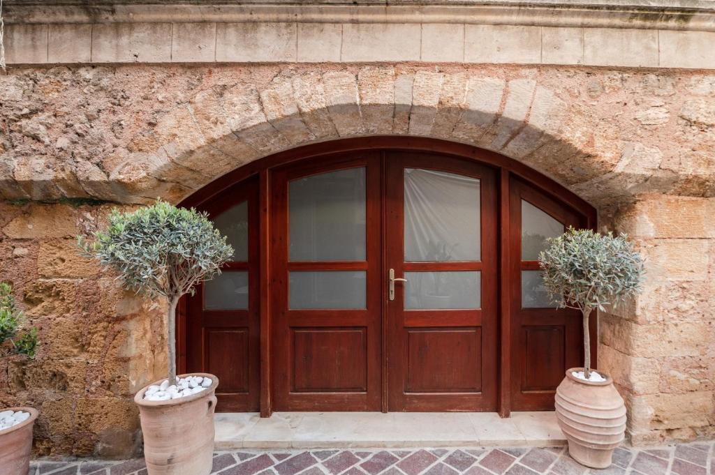 une porte en bois dans un bâtiment en pierre avec deux plantes en pot dans l'établissement Hanim Boutique Hotel, à La Canée