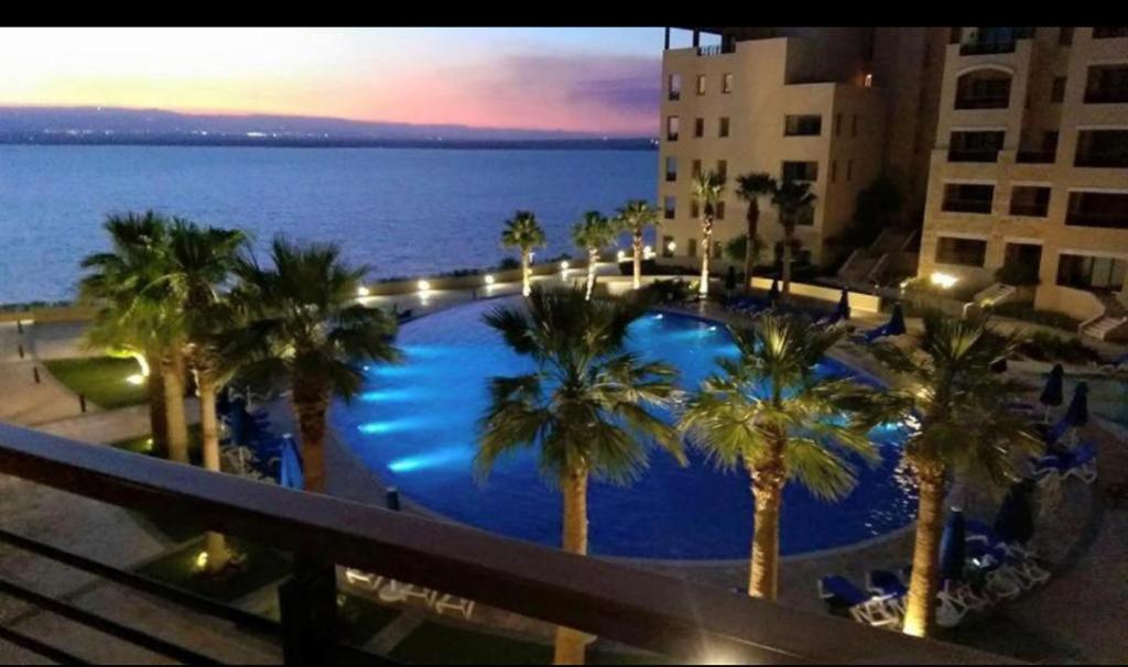 サワイマにあるDead Sea view Elite apartment Samara Resort traveler award 2024のヤシの木が茂るスイミングプールの景色を望むバルコニーが備わります。