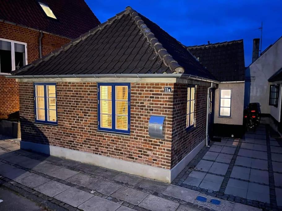 una casa de ladrillo con persianas azules y amarillas en Hyggeligt lille byhus lige mellem havnen og bytorv, en Ringkøbing