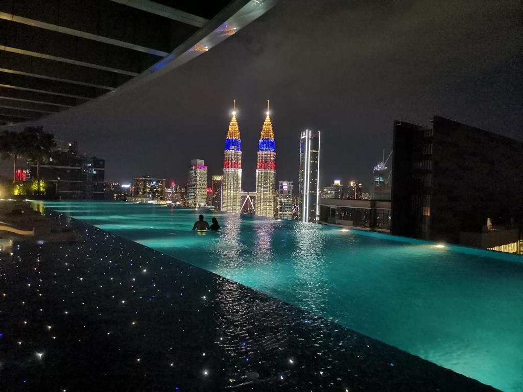 uma piscina com um horizonte da cidade à noite em EATON RESIDENCE AT KLCC em Kuala Lumpur