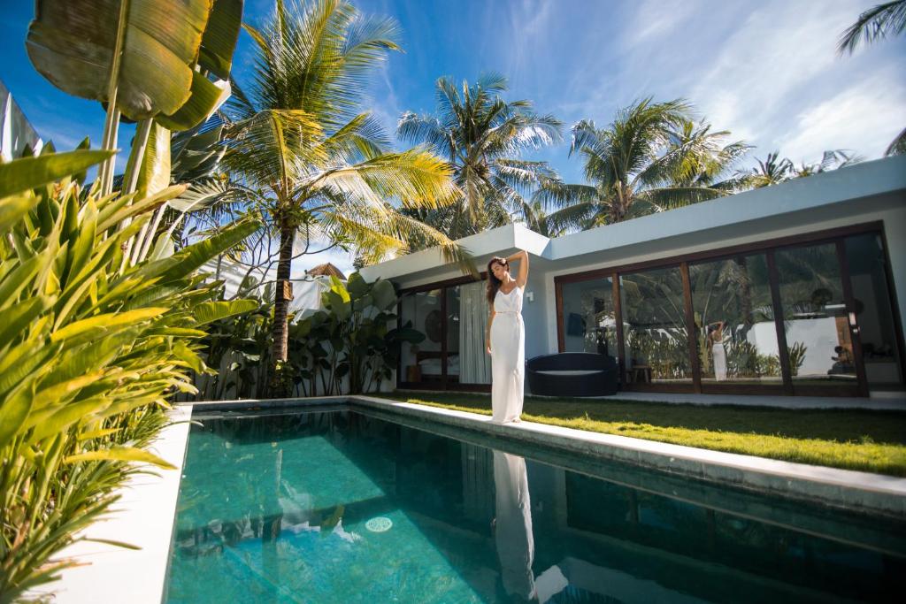 Eine Frau in einem weißen Hochzeitskleid, die neben einem Pool steht. in der Unterkunft Kalea Villas in Kuta Lombok