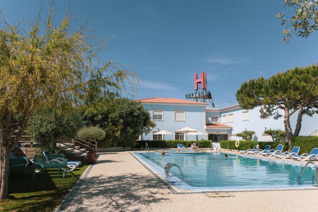 una piscina con tumbonas y un edificio en Hotel Neptuno, en Atouguia da Baleia