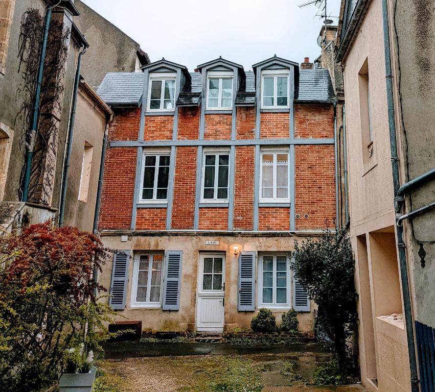 een groot bakstenen gebouw met witte ramen en luiken bij Charmante maison front de mer et centre ville in Luc-sur-Mer