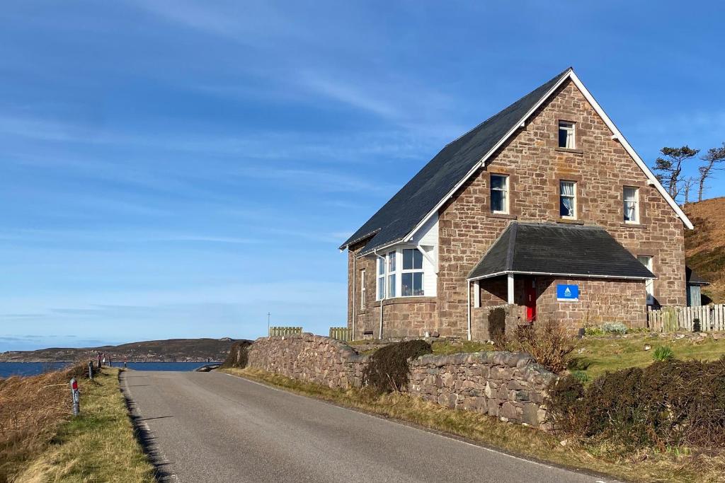 una casa in pietra sul lato di una strada di Gairloch Sands Youth Hostel a Gairloch