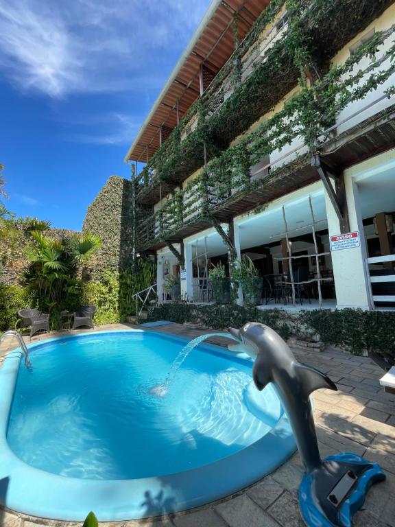 a dolphin fountain in a pool in front of a building at Pousada Beijos y Abraços in Natal