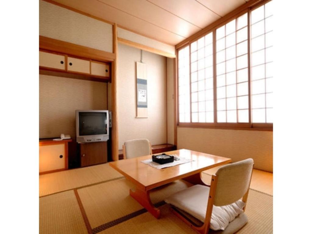 Habitación con mesa, sillas y TV. en Tennen Onsen Kakenagashi no Yado Hotel Pony Onsen - Vacation STAY 50911v, en Towada