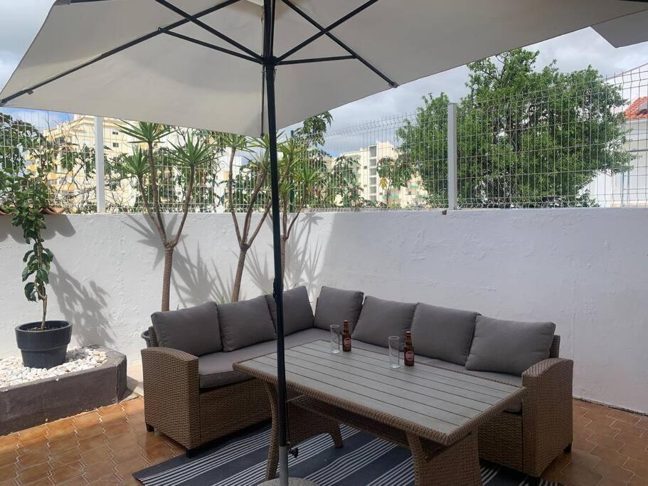 a couch and an umbrella on a patio at Nossa Casa - 2 Bedroom Apartment in Alvor in Alvor