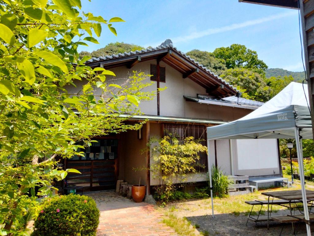 ein Haus mit einem Tisch und einem Zelt davor in der Unterkunft 88 House Hiroshima in Hiroshima