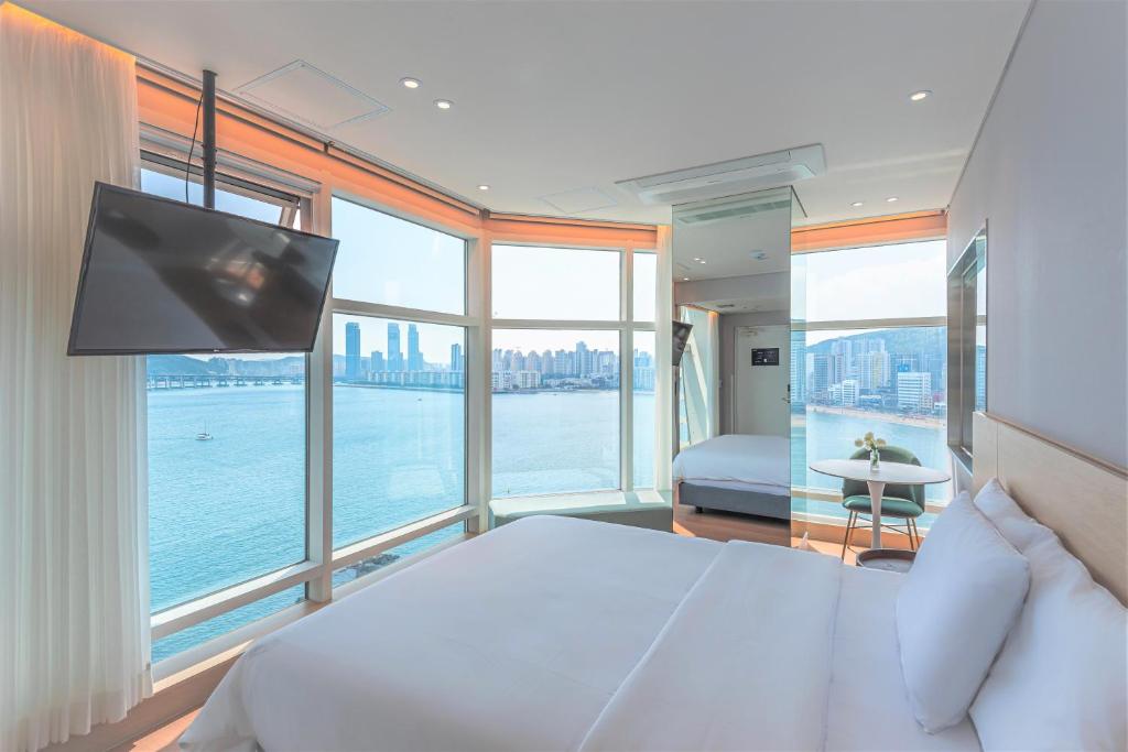 una camera con un grande letto, una TV e finestre di Hotel Marine view a Busan