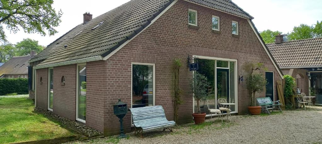 una casa di mattoni con una panchina davanti di De Oude Smederij a Noord-Sleen