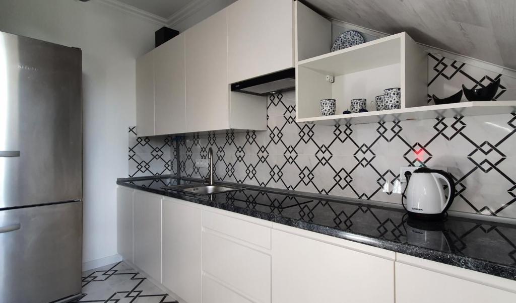 a kitchen with white cabinets and black and white tiles at Апартаменти - Історія з вікна in Kamianets-Podilskyi