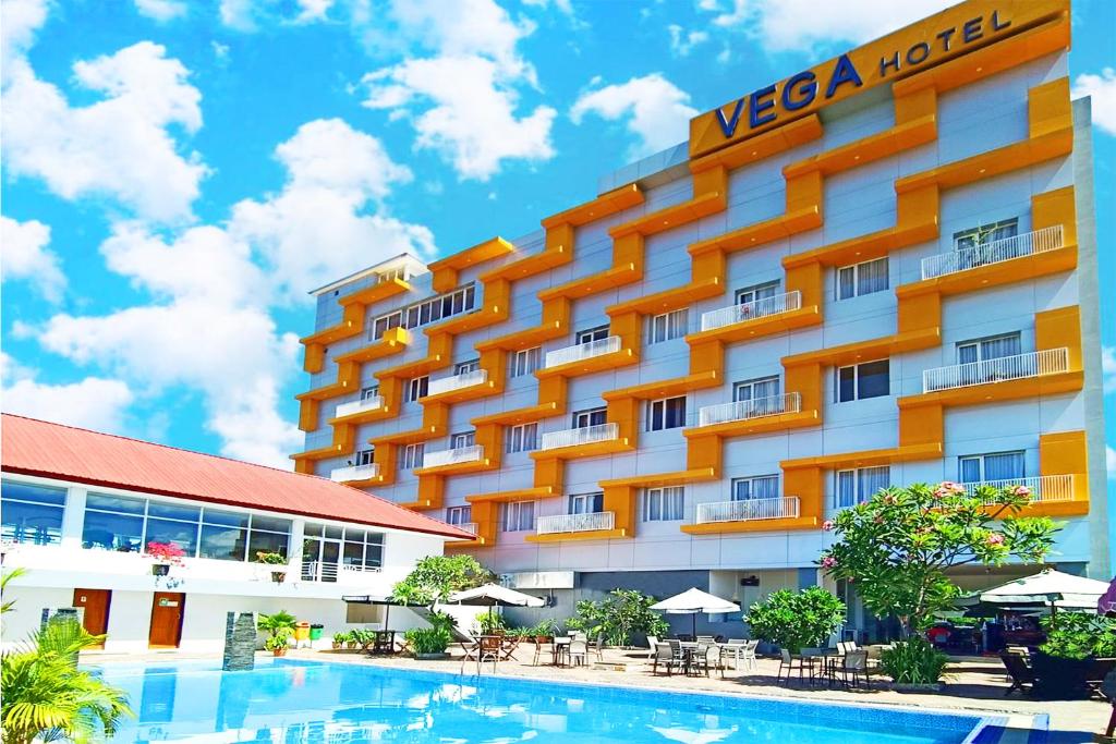 a hotel with a swimming pool in front of a building at Vega Prime Hotel & Convention in Sorong