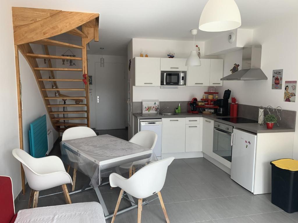 - une cuisine avec des placards blancs, une table et des chaises dans l'établissement Charmante maisonnette à Quend Plage, 2 chambres, jardinet, parking, proche commodités - FR-1-482-45, à Quend