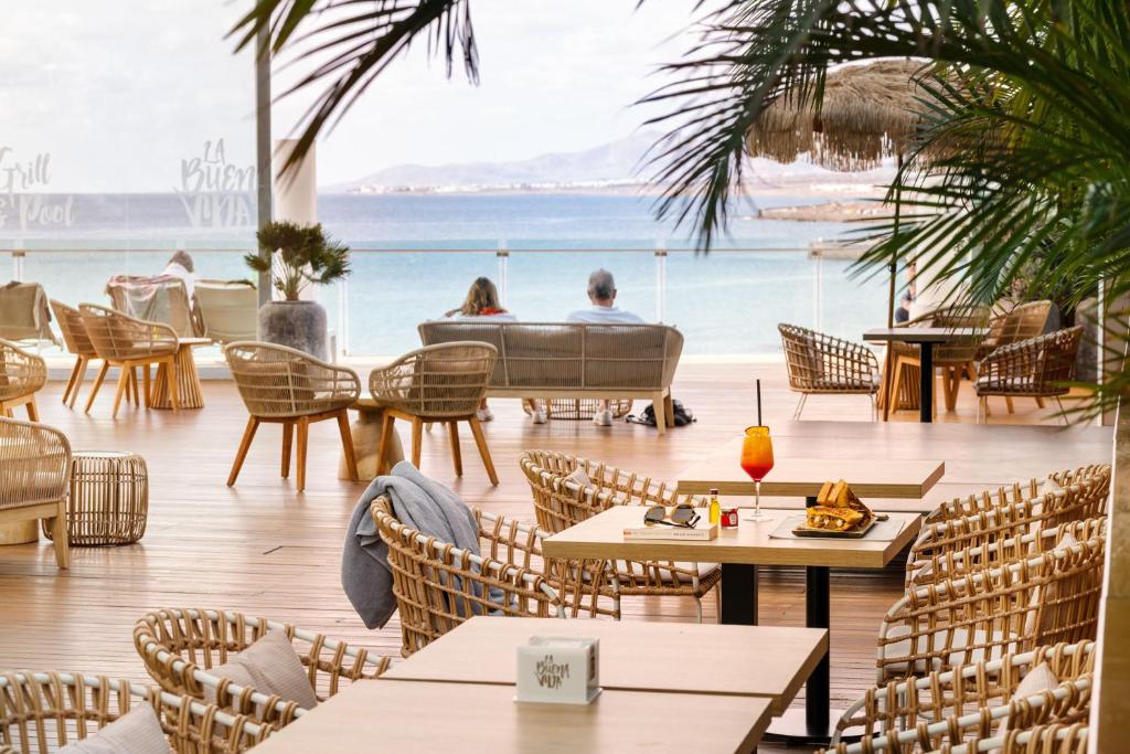 een restaurant met tafels en stoelen en uitzicht op de oceaan bij Arrecife Gran Hotel & Spa in Arrecife