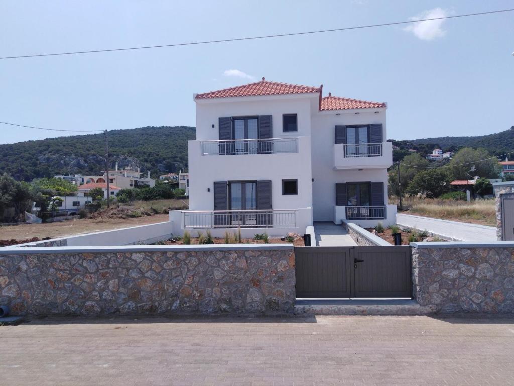 une maison blanche avec une clôture devant elle dans l'établissement Agistri Beach, à Skala