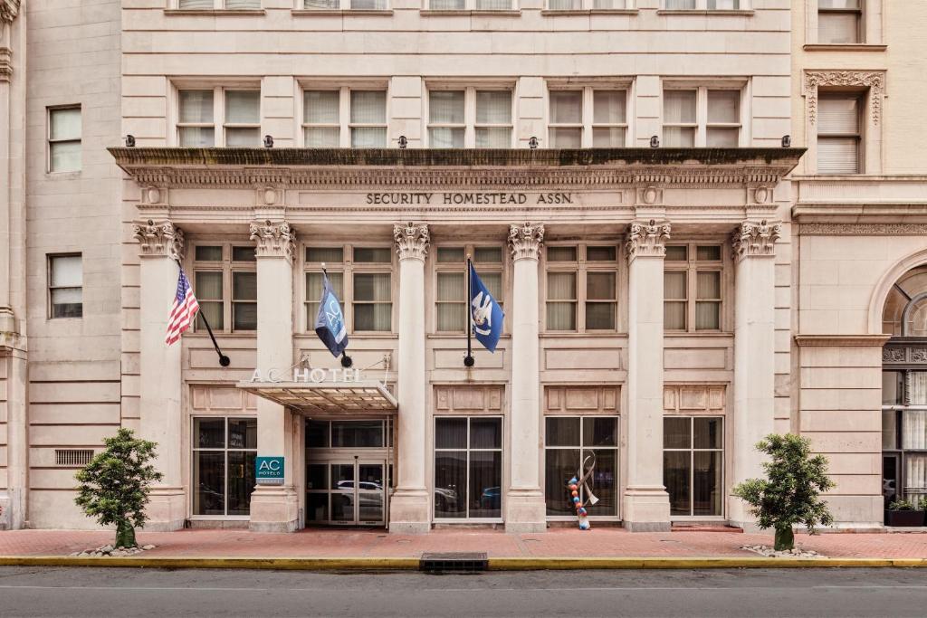 AC Hotel by Marriott New Orleans French Quarter في نيو أورلينز: مبنى كبير به أعلام أمامه