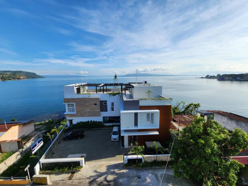 eine Luftansicht eines Hauses neben dem Wasser in der Unterkunft PURNAMA BALIGE HOTEL in Balige