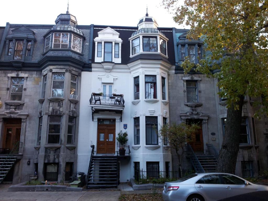 uma casa branca com um carro estacionado em frente dela em Gingerbread Manor em Montréal