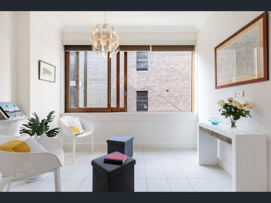 un soggiorno bianco con lampadario pendente e finestra di Stylish apartment in the heart of Potts Point a Sydney