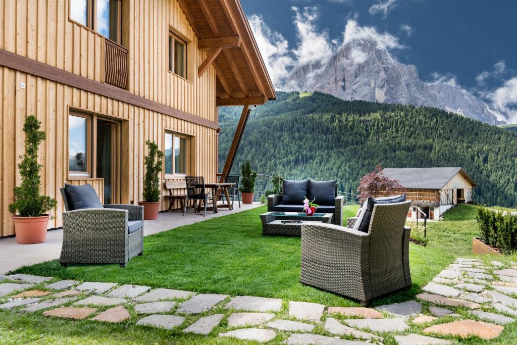 patio z krzesłami i stołem z górami w obiekcie Villa Solinda App Puccini w mieście Selva di Val Gardena