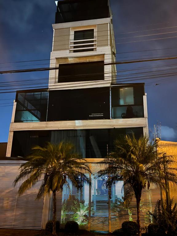 un edificio alto con palmeras delante en Talli Hotel, en Curitiba