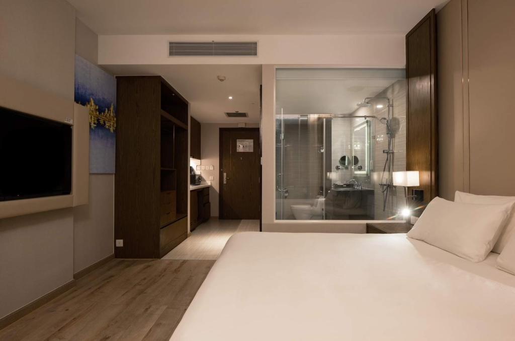 - une chambre avec un grand lit blanc et une télévision dans l'établissement Panorama apartment Nha Trang, à Nha Trang