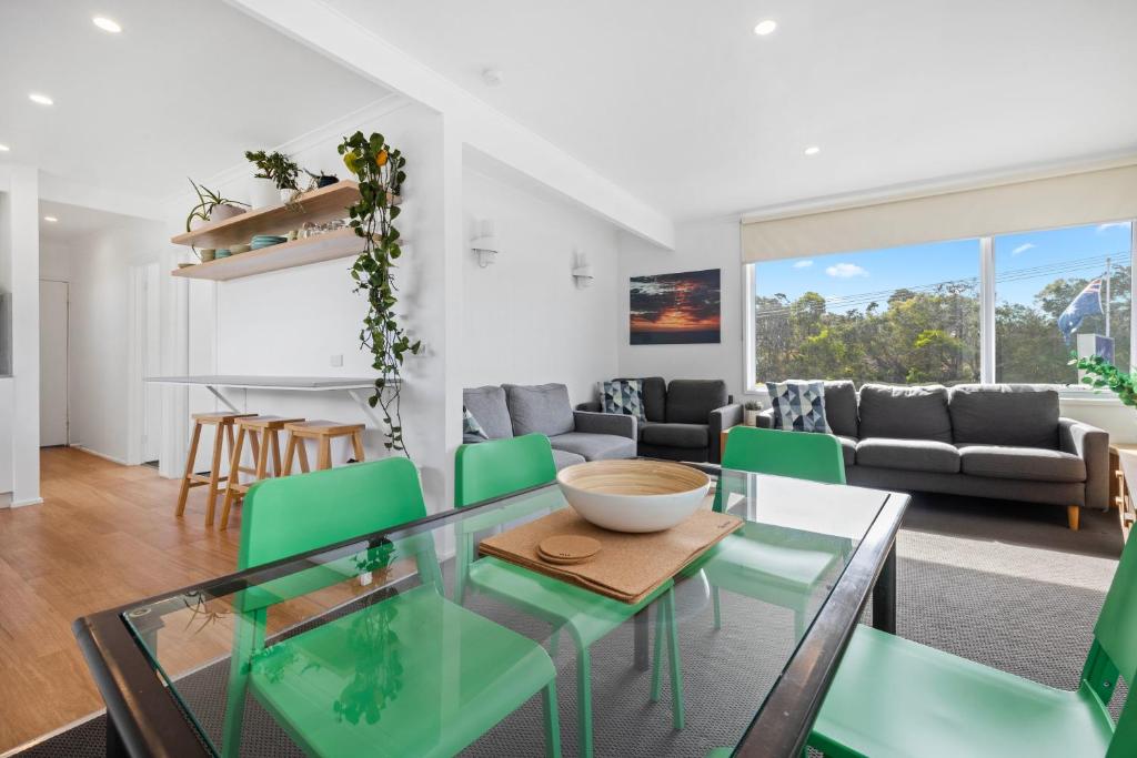 uma sala de estar com uma mesa de vidro e cadeiras verdes em Moody's Beach Apartment em Blairgowrie