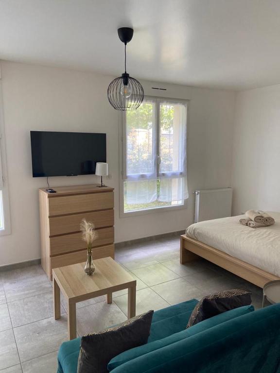 a bedroom with a bed and a tv and a couch at Grand Studio neuf in Aulnay-sous-Bois