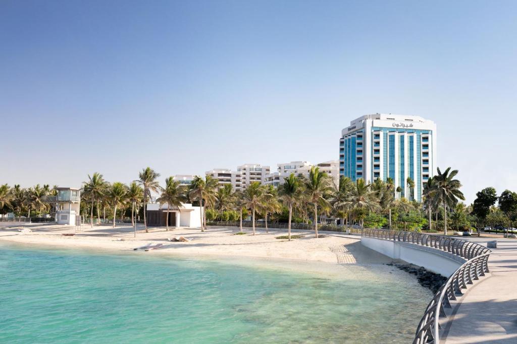 una spiaggia con palme e un edificio alto di Sheraton Jeddah Hotel a Gedda