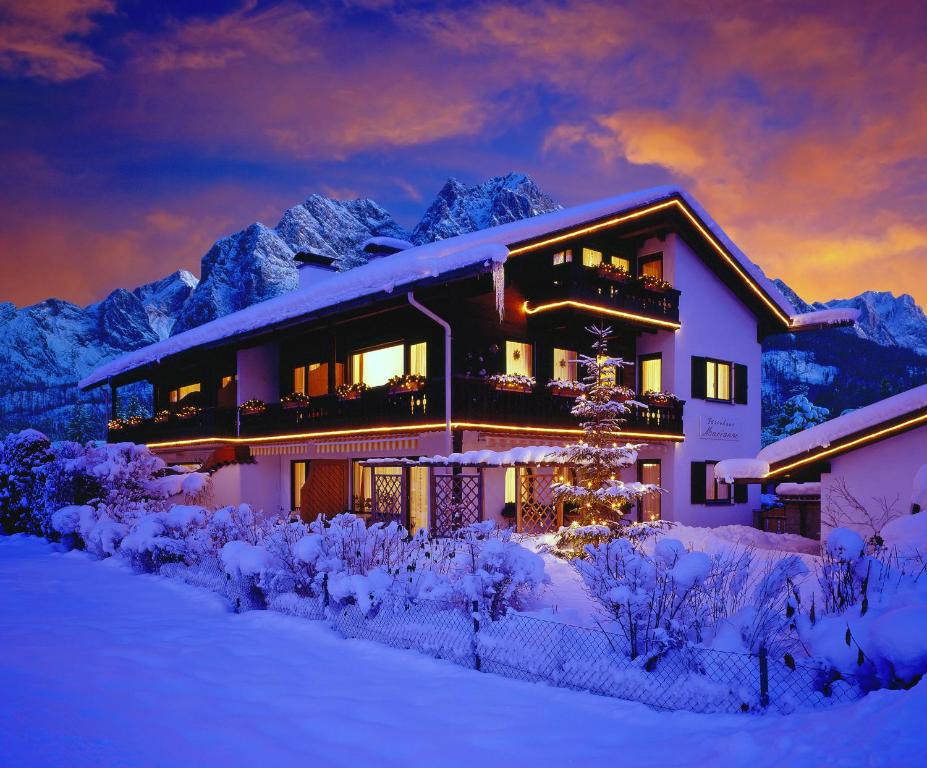 une maison dans la neige devant les montagnes dans l'établissement Gästehaus Marianne, à Grainau