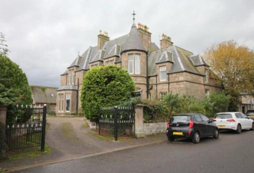 una casa grande con coches estacionados frente a ella en Duchally House, en Nairn